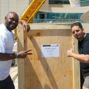 Two gentlemen standing with a wooden crate