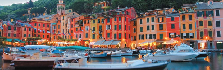 Boats on the water in front of red and orange and red buildings